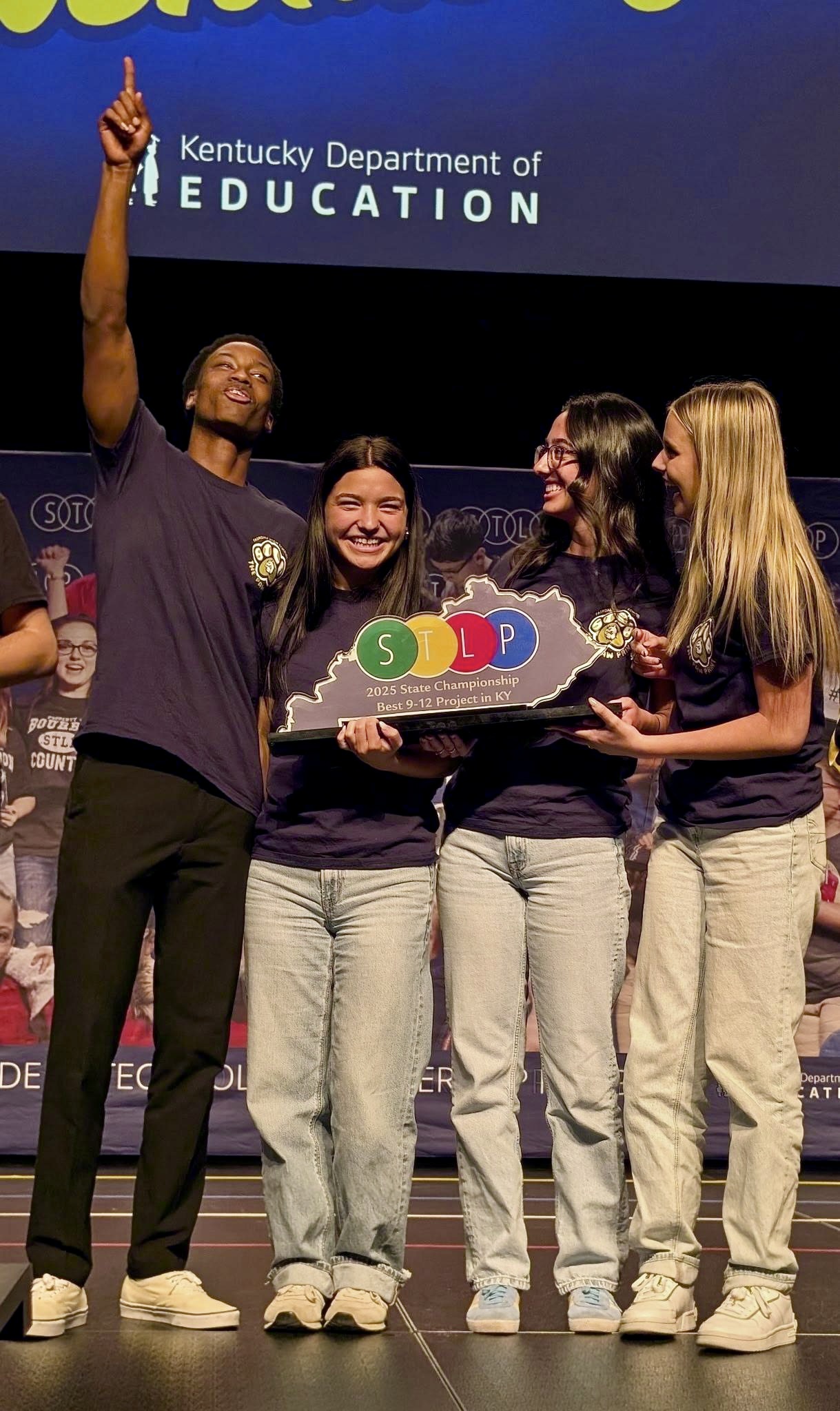 STLP student champions celebrat3e their win holding trophy and raising victory symbolically overhead